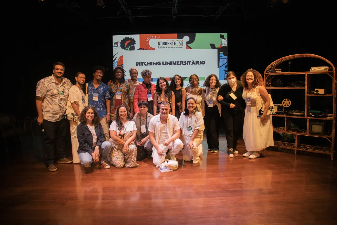 Foto de grupo no palco, sob o telão do Pitching Universitário